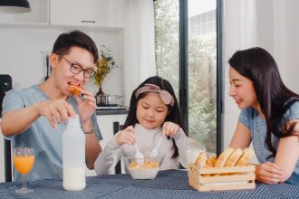 Anak sedang sarapan sehat sebelum berangkat sekolah bersama orang tua.