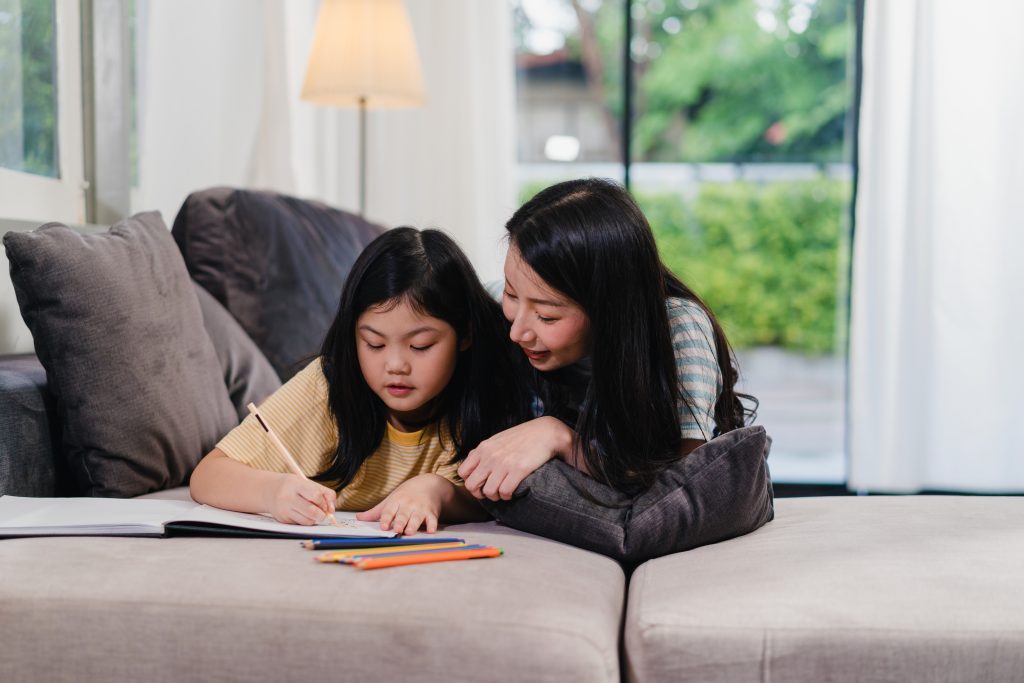 Ibu mendampingi anak belajar sambil memberikan dukungan emosional dan membaca buku bersama.
