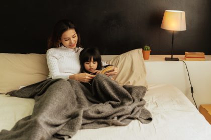 Ibu membaca buku sebelum tidur sambil mengajak anak berbicara
