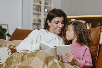 Ibu membaca buku sebelum tidur sambil mengajak anak berbicara