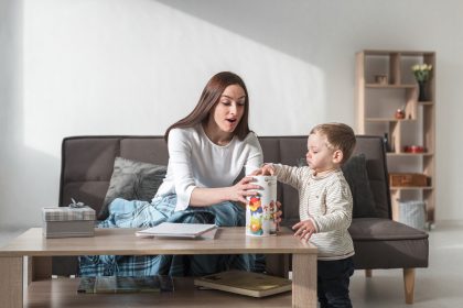 ibu mendampingi anak mengucapkan kata pertama saat bermain di rumah