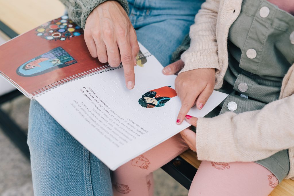 Ibu membaca buku secara interaktif bersama anak dan menunjuk gambar