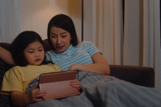Ibu dan anak melakukan rutinitas sebelum tidur sambil membaca dan mengobrol untuk melatih bicara
