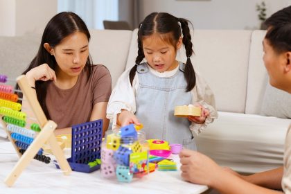 Anak mengelompokkan balok berdasarkan warna dan bentuk saat bermain bersama ibu di rumah.