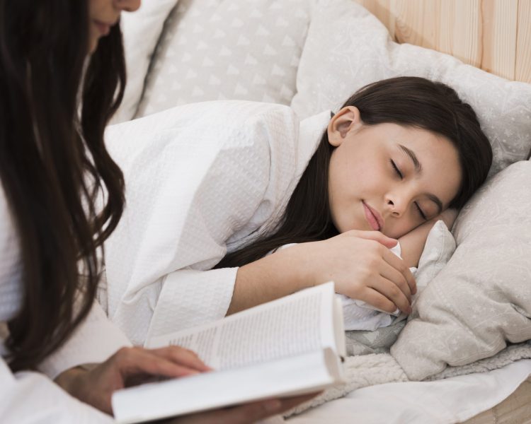 Orang tua membacakan buku sebelum tidur sebagai bagian dari rutinitas tidur sehat anak.