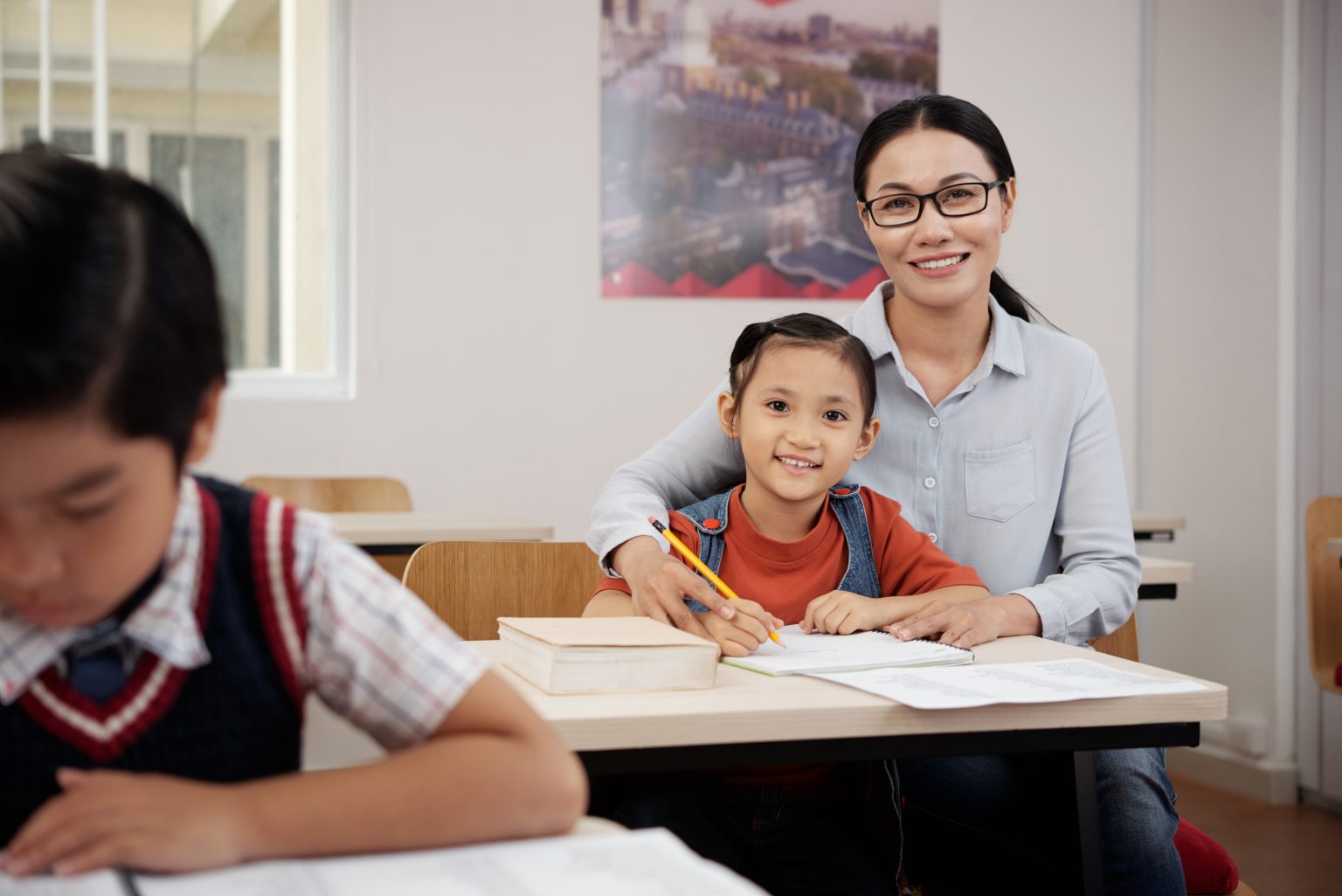 Guru membantu siswa mempersiapkan pelajaran sambil melatih kemandirian saat hari pertama sekolah.