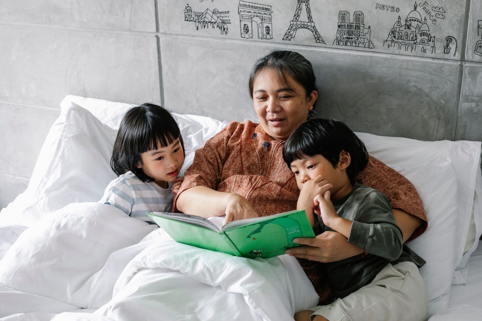 Ibu membaca buku sebelum tidur untuk mendukung bahasa anak.