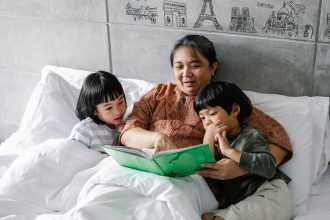 Ibu membaca buku sebelum tidur untuk mendukung bahasa anak.