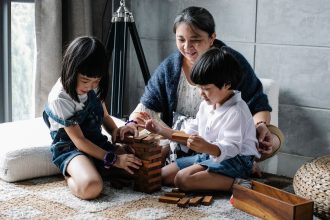 Orang tua mendampingi anak mengakhiri screen time dan beralih ke permainan balok di rumah.
