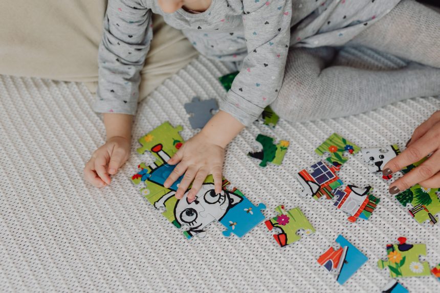 Ibu mendampingi anak yang kesal saat menyusun puzzle di rumah