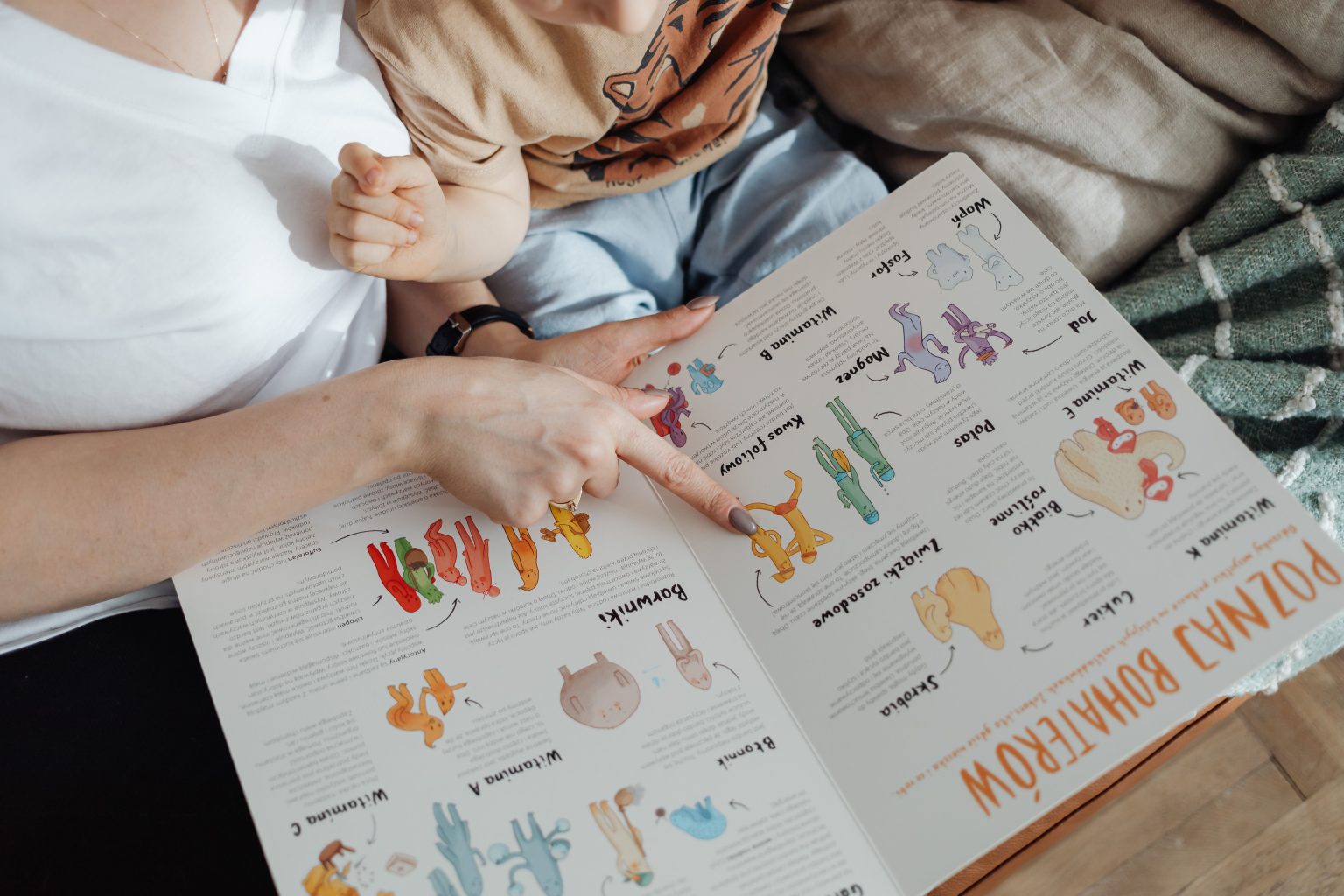 Ibu dan anak membaca buku interaktif sambil menunjuk gambar hewan