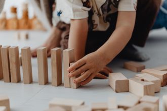 Bunda mendampingi anak menyusun balok untuk melatih problem solving melalui permainan.