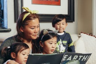Ibu membaca buku interaktif bersama anak sambil menunjuk gambar