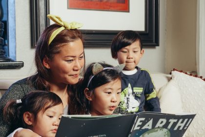 Ibu membaca buku interaktif bersama anak sambil menunjuk gambar