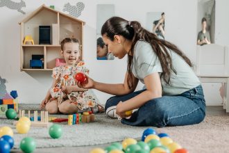 Anak dan ibu mencoba lintasan bola dari kardus untuk belajar sebab-akibat